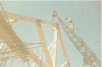Walter up on ladder on top of framing of house.