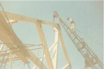 Walter up on ladder on top of framing of house.