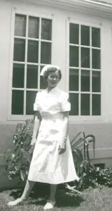 A young Evelyn Thielemann in nurse uniform outside a home. 